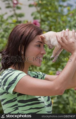 Side profile of a young woman playing with a puppy and smiling
