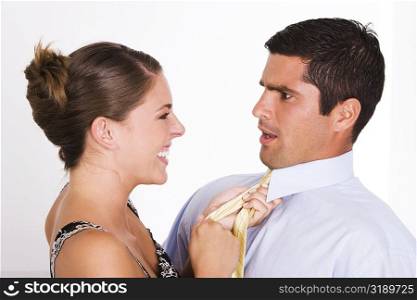 Side profile of a young woman pulling a mid adult man with his tie