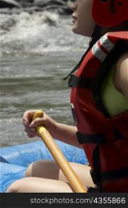 Side profile of a young woman rafting in a river