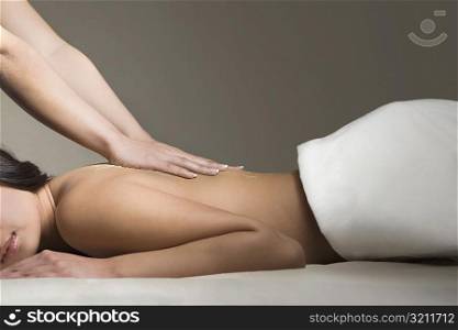 Side profile of a young woman receiving a back massage from a massage therapist