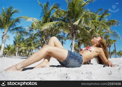 Side profile of a young woman reclining on the beach