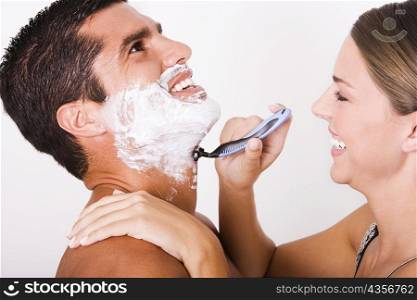 Side profile of a young woman shaving a mid adult man