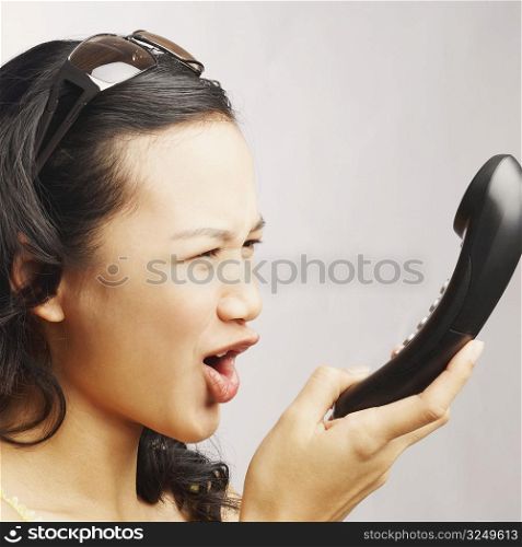Side profile of a young woman shouting on the phone