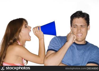 Side profile of a young woman shouting with a megaphone into a young man&acute;s ear