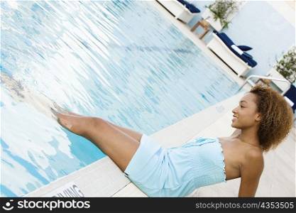 Side profile of a young woman sitting at the poolside