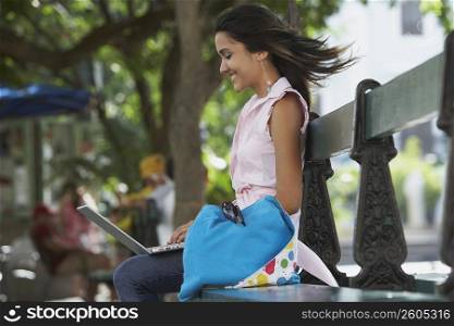 Side profile of a young woman sitting in a park and using a laptop, Old San Juan, San Juan, Puerto Rico