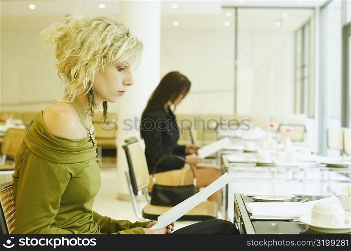 Side profile of a young woman sitting in a restaurant and holding a menu card