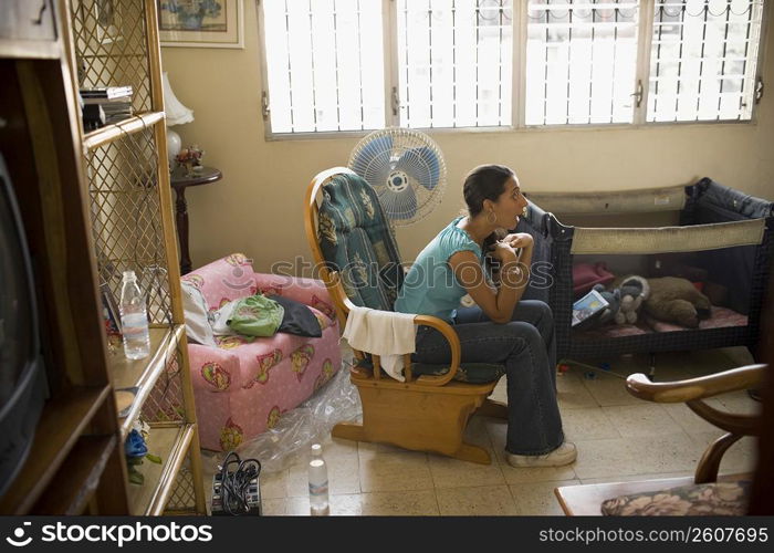 Side profile of a young woman sitting in an armchair and looking surprised