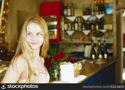 Side profile of a young woman smiling at a bar counter