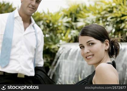 Side profile of a young woman smiling with a young man standing in front of her