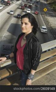 Side profile of a young woman standing on an overpass looking away
