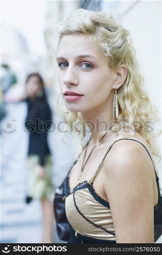 Side profile of a young woman standing on the sidewalk