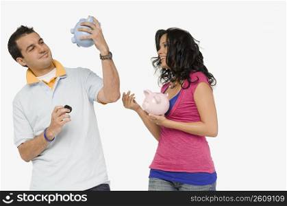Side profile of a young woman standing with a young man looking at a piggy bank
