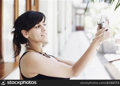 Side profile of a young woman taking a photograph of herself