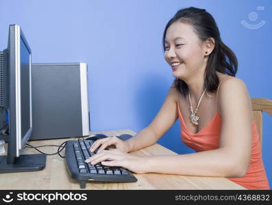 Side profile of a young woman using a computer and smiling