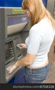 Side profile of a young woman using an ATM machine