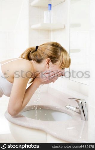 side profile of a young woman washing her face in a basin
