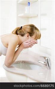 side profile of a young woman washing her face in a basin