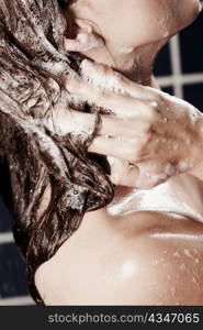 Side profile of a young woman washing her hair with shampoo