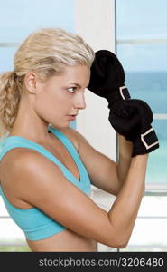 Side profile of a young woman wearing boxing gloves
