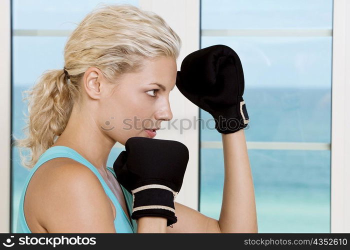 Side profile of a young woman wearing boxing gloves