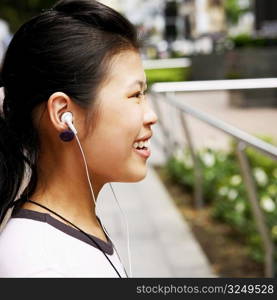 Side profile of a young woman wearing headphones and listening to music