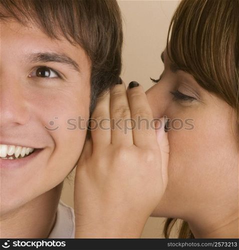 Side profile of a young woman whispering to a young man