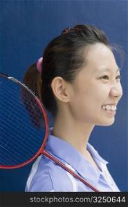 Side profile of a young woman with a badminton racket and smiling