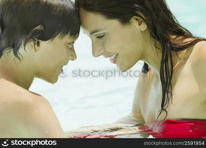 Side profile of a young woman with her son face to face in a swimming pool