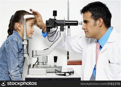 Side profile of an optometrist examining a girl&acute;s eye