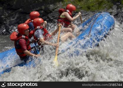 Side profile of four people rafting in a river
