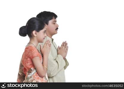 Side profile of kids dressed as husband and wife praying