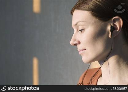 Side profile of redhead listening to headphones