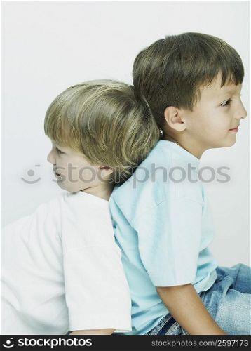 Side profile of two boys sitting back to back