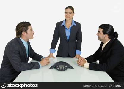 Side profile of two businessmen and a businesswoman in a conference room