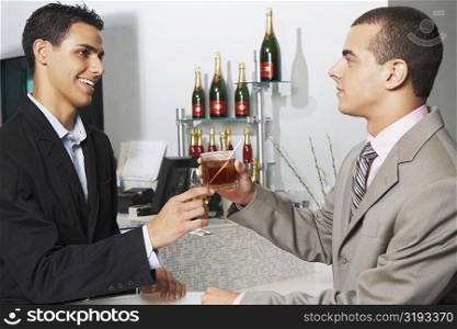 Side profile of two businessmen toasting their glasses