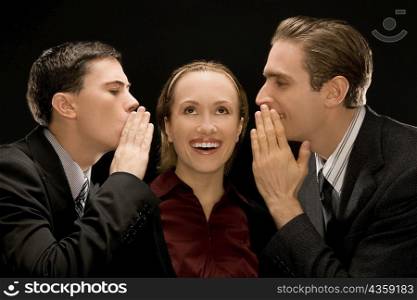 Side profile of two businessmen whispering to a businesswoman