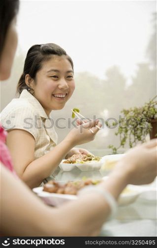 Side profile of two female office workers having lunch and smiling