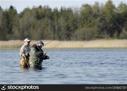 Side profile of two mature men fishing in the river