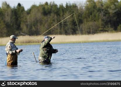 Side profile of two mature men fishing in the river