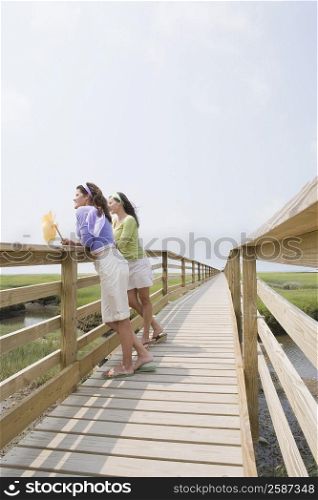 Side profile of two mature women standing on a wooden bridge