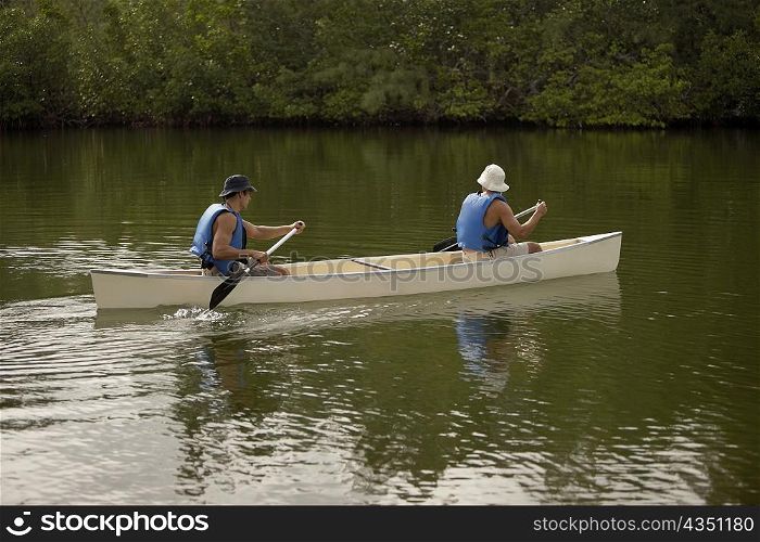 Side profile of two mid adult men canoeing