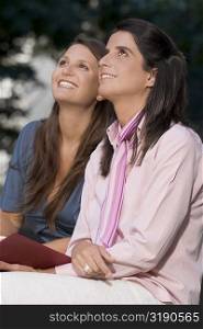Side profile of two mid adult women sitting together and smiling