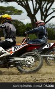 Side profile of two motocross riders riding motorcycles