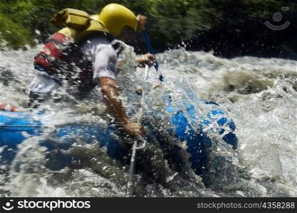 Side profile of two people rafting in a river