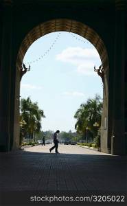Side profile of two people walking on the footpath in front of an arch, Victoria Memorial, Laos