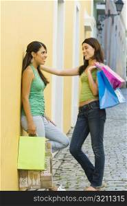 Side profile of two teenage girls facing each other and holding shopping bags