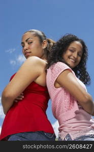 Side profile of two teenage girls standing back to back