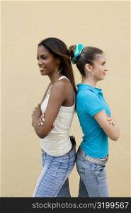 Side profile of two teenage girls standing back to back