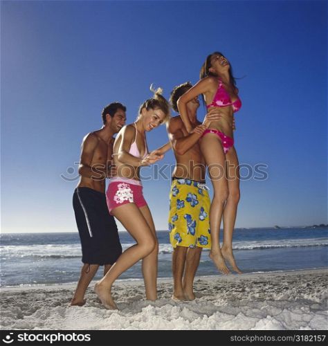 Side profile of two young couples on the beach